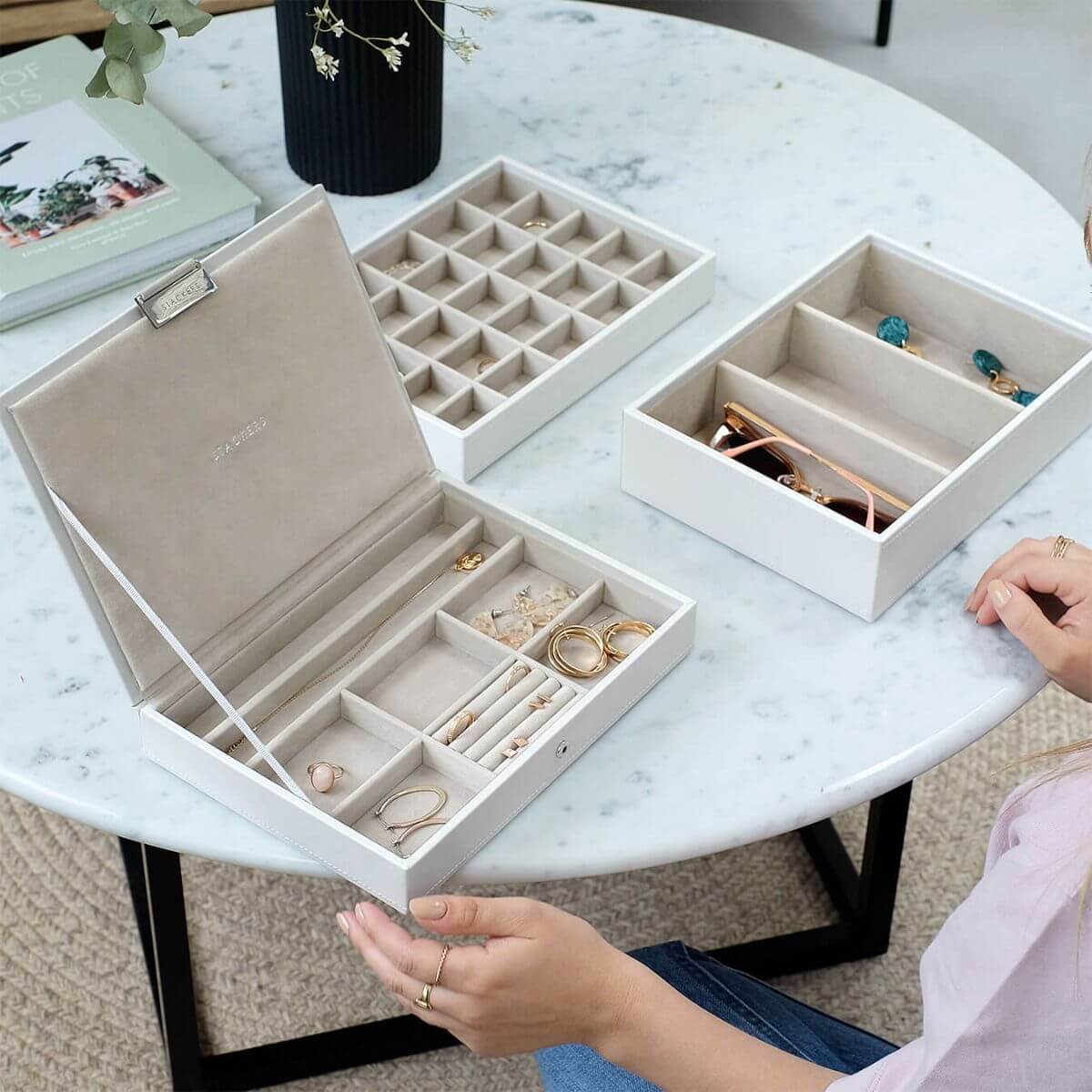 Three white Stackers jewellery storage trays on a white marble table