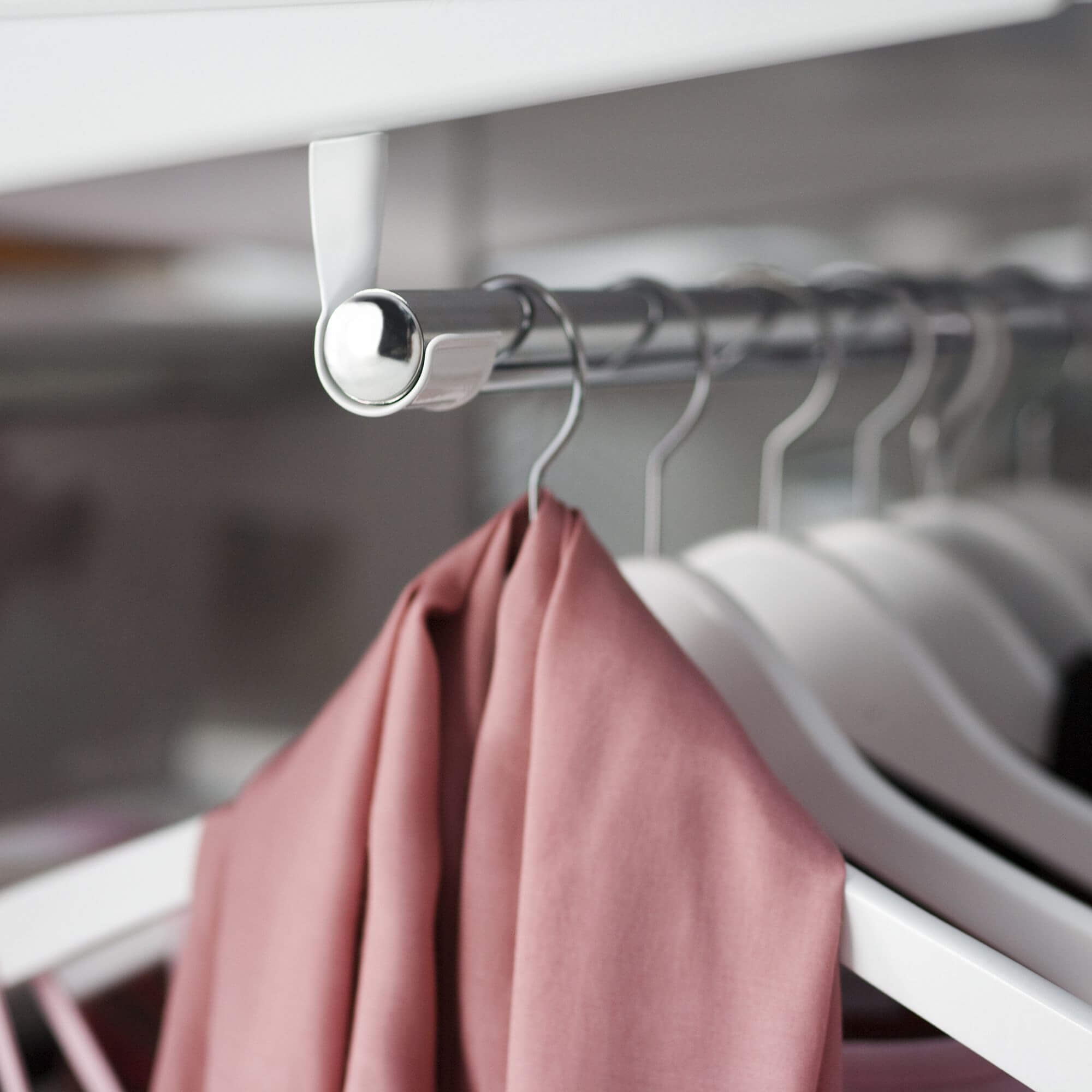 White coat hangers on an Elfa Closet Rod in nickel finish