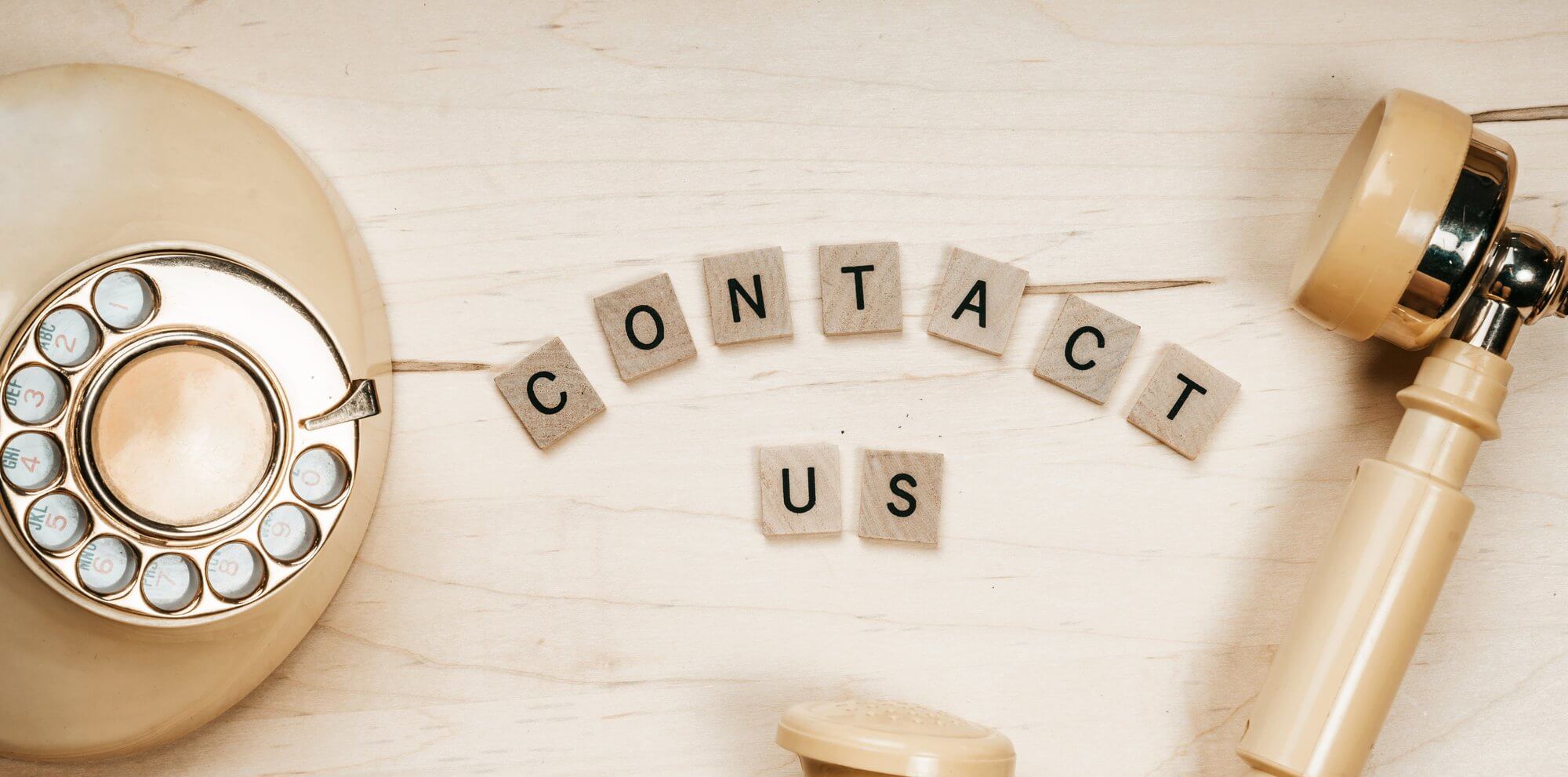 A beige phone next to a sign reading "Contact Us"