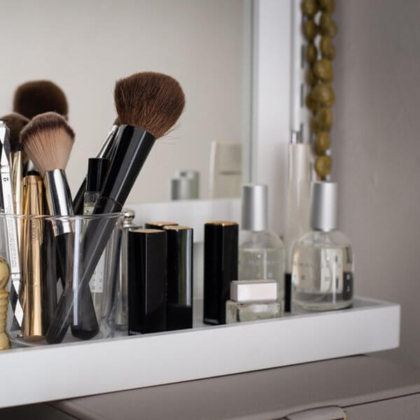 A slim White Elfa Decor Accessory Shelf installed in a wardrobe for organising perfume bottles and makeup