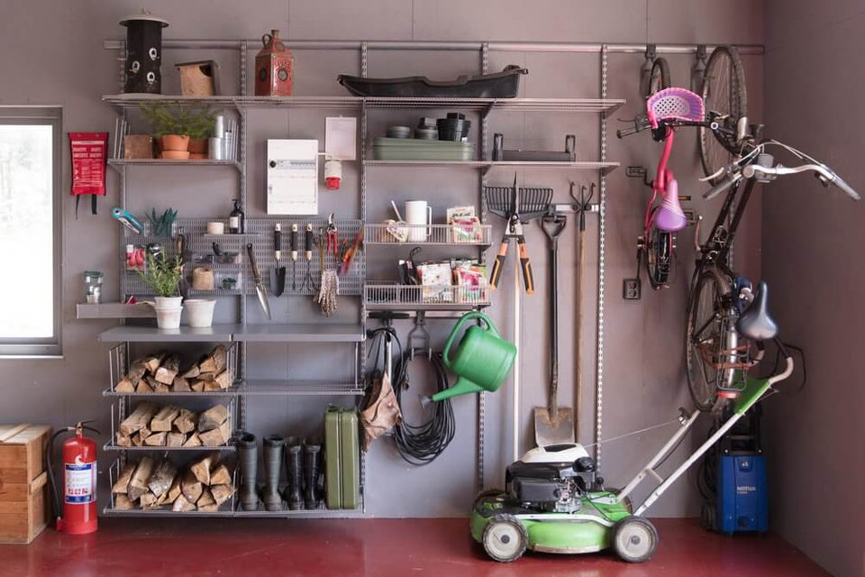 A Platinum Elfa garage shelving system with firewood, bicycles and shovels stored inside