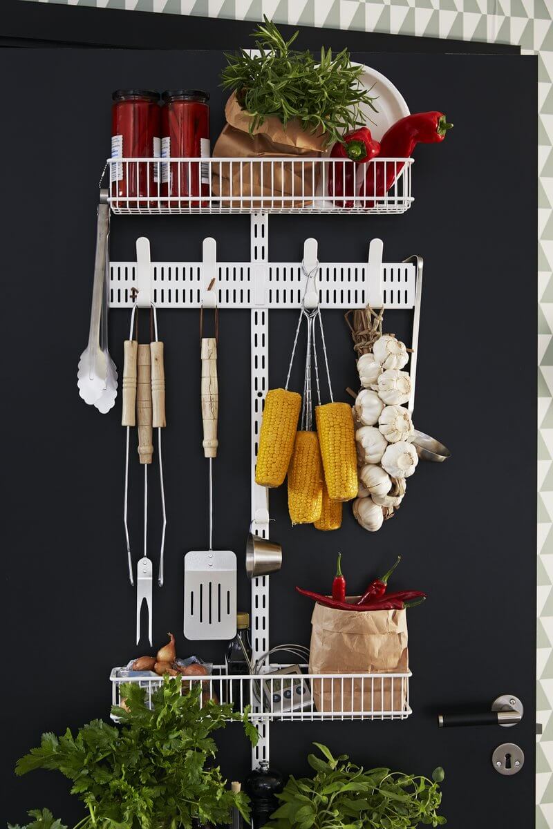 A White Elfa Utility Wall & Door system with Wire Utility Baskets and a Centre Storing Board, used for over-the-door pantry and produce storage in the kitchen