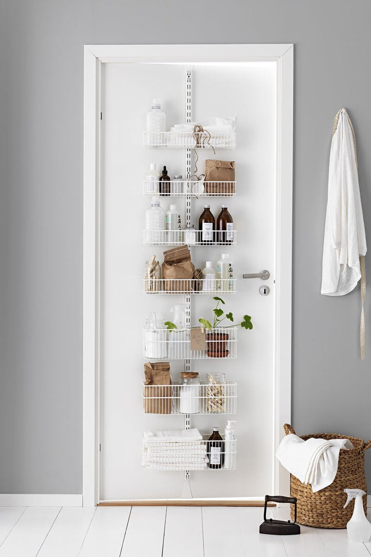 A White Elfa Utility Wall & Door system with Wire Utility Baskets, used for over-the-door bathroom storage