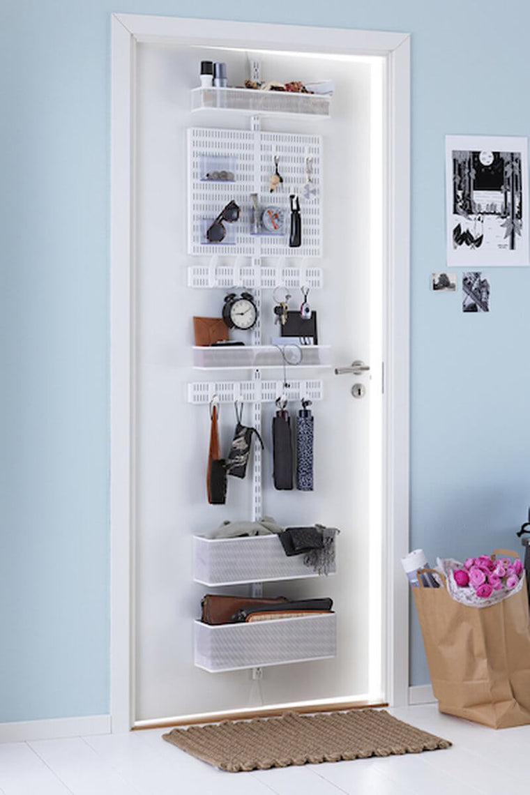 A White Elfa Utility Wall & Door system with Mesh Utility Baskets and a Centre Storing Board, used for over-the-door storage of umbrellas, brushes and glasses